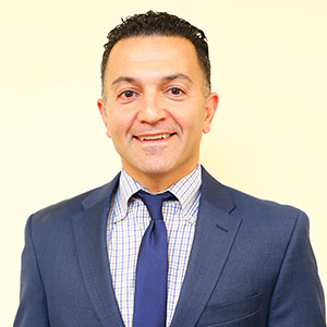 A man in a suit and tie smiling for the camera.